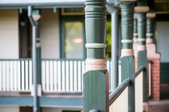 Turned timber verandah post - green and pink turned posts along a verandah with balustrade