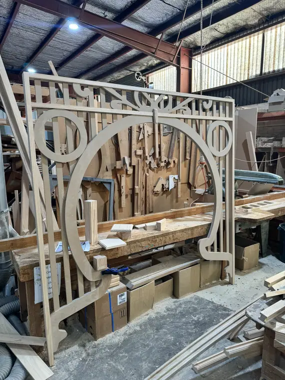An ornate curved balustrade panel being assembled on the workshop bench.
