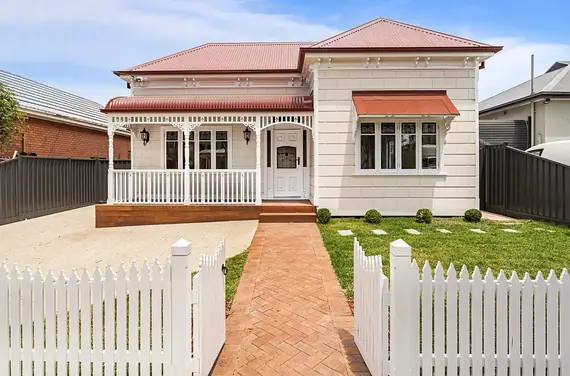 Turned posts and fretwork on a verandah behind a white picket fence