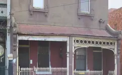 Before restoration: a pair of terraces with faded paint and a rusting verandah roof