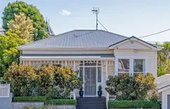 Verandah fretwork and picket fence on a restored cream weatherboard period home