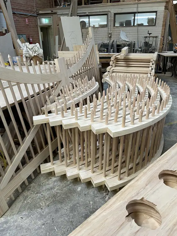 Curved timber balustrade with turned finial-top balusters, in the workshop
