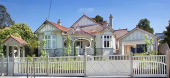 Heritage decorative timber - green and white verandah fretwork across a Federation house