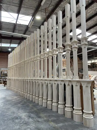A long row of newly finished decorative verandah posts standing in the Bayswater workshop.