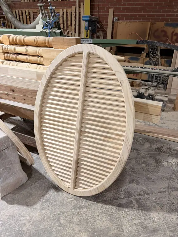 An oval timber louvre vent with a deep moulded surround.