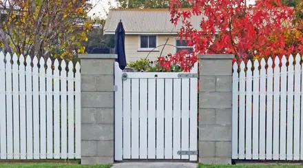 Mackay timber gate set into a white picket fence between rendered piers