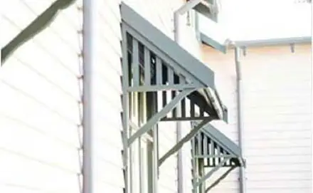 Two green window canopies above sash windows, weatherboard wall behind