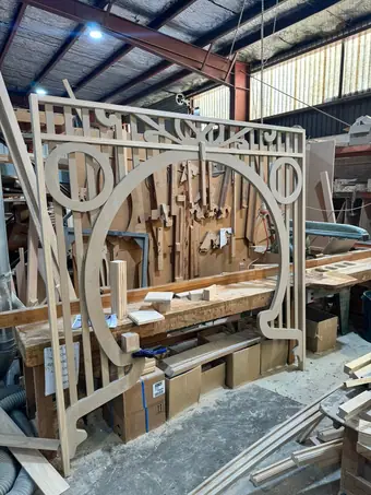 Timber finishing - an arched fretwork panel standing in the workshop, hand tools by it