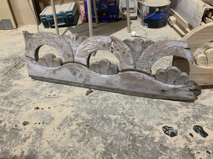 Weathered painted fretwork sample with curved openings and decorative motifs