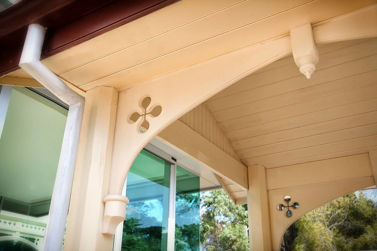Timber corner bracket - curved corner bracket with a quatrefoil pierce under a lined verandah roof