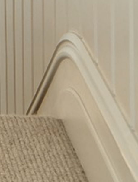 Close-up of a finished stair side with a moulded skirting against carpeted treads