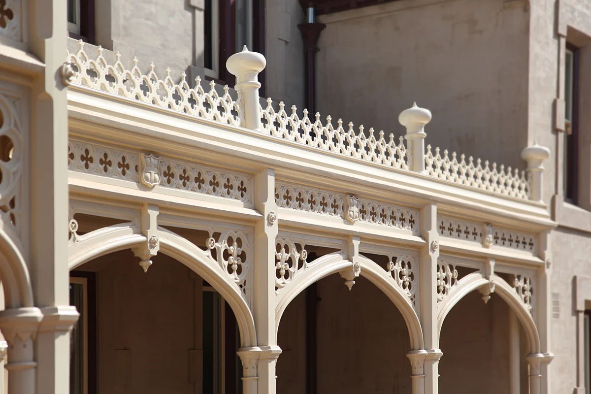 Cream arched fretwork spanning three verandah openings, with a quatrefoil pierced frieze and onion-domed finials above