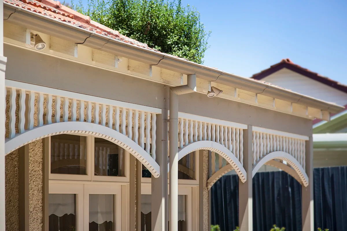 Three arched fretwork valances in a row along a verandah, seen from the garden