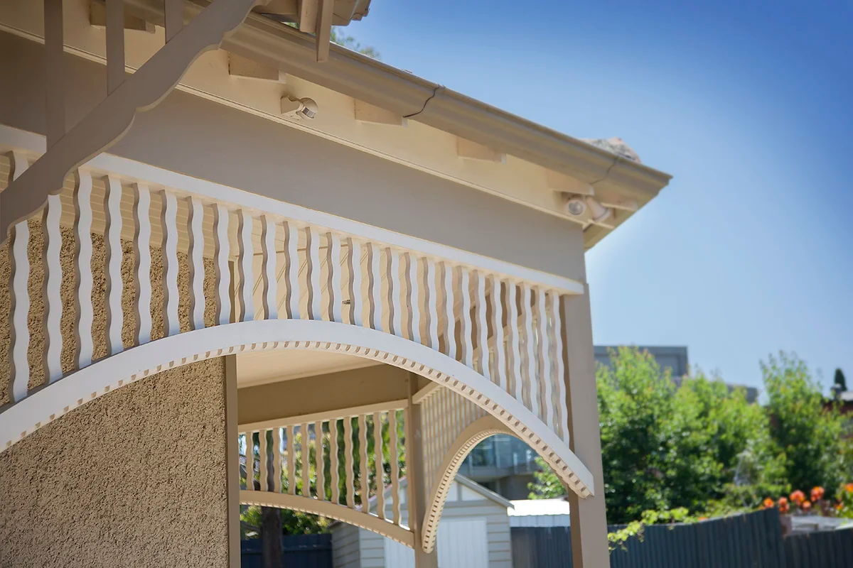 Arched fretwork at a verandah corner, wavy balusters standing above the curve of the arch
