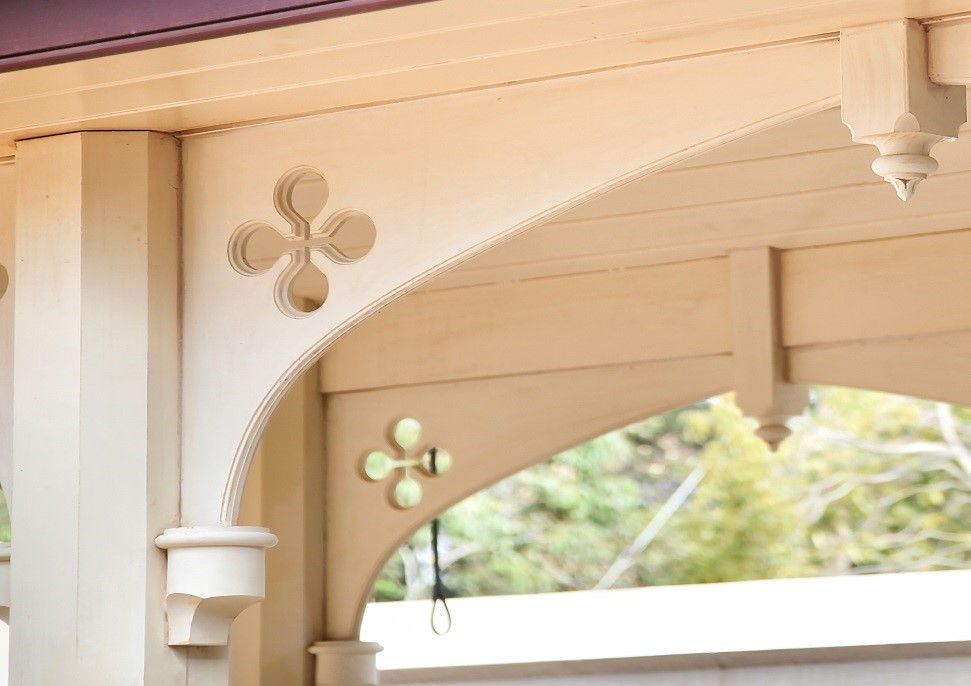 One arched fretwork bracket in close-up, a quatrefoil pierced through the spandrel