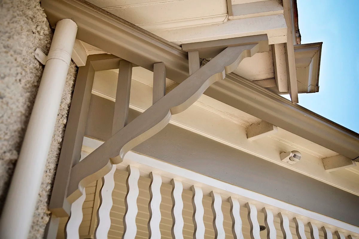 Timber corner brackets above a run of shaped slat balusters, under the eaves